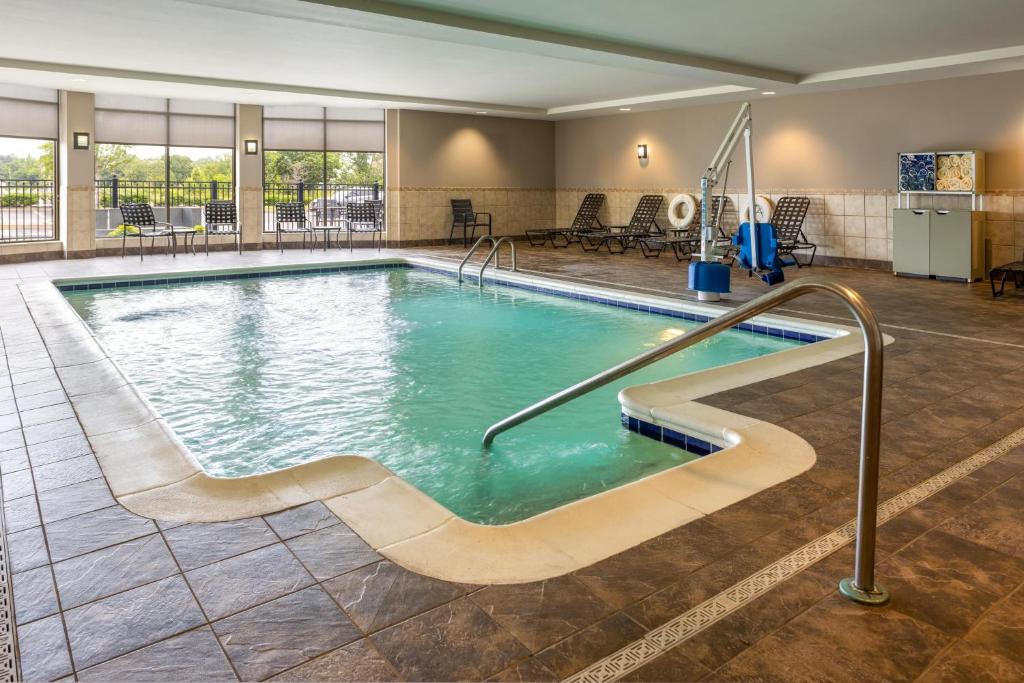 einen Pool in einem Hotelzimmer mit Tischen und Stühlen in der Unterkunft Hilton Garden Inn Memphis/Wolfchase Galleria in Memphis