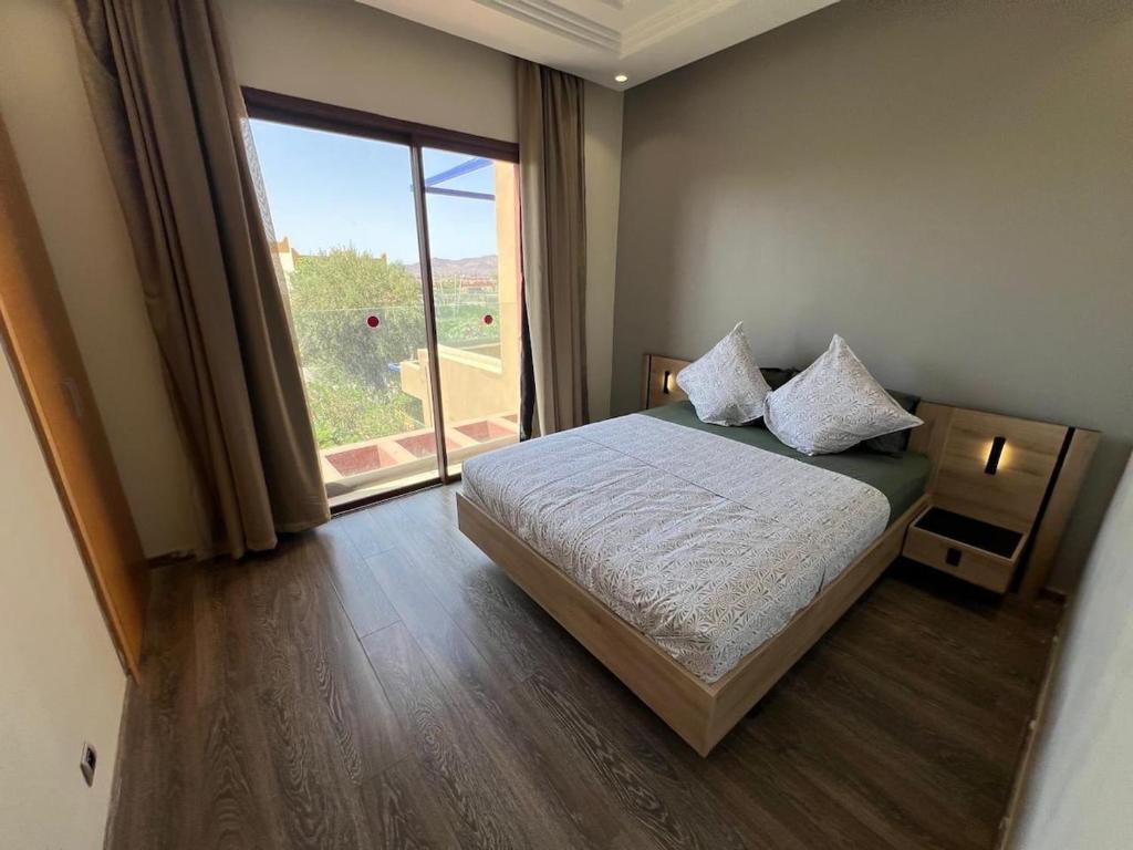a bedroom with a bed and a large window at Appartement de charme au Vizir Resort in Dar Caïd Layadi
