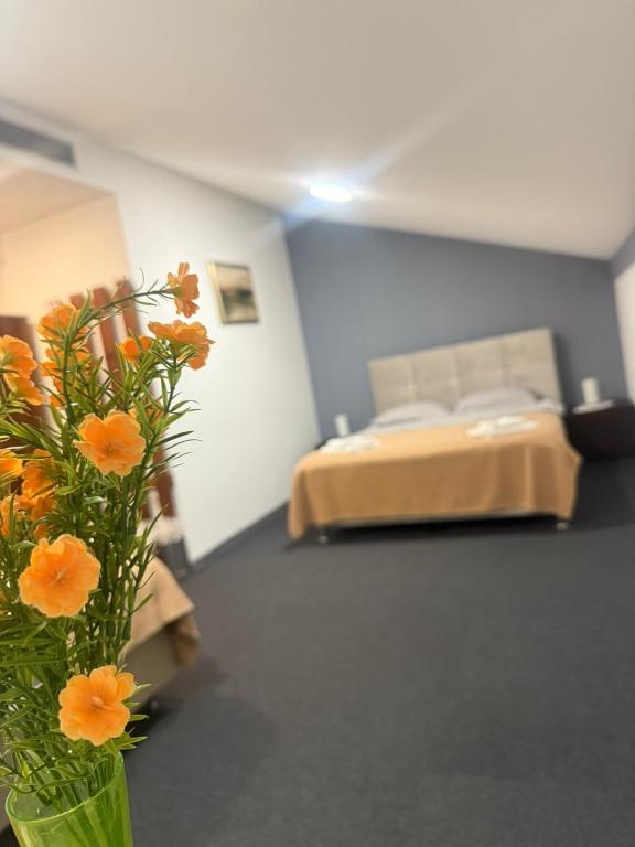 a bedroom with a bed and a vase with orange flowers at Hotel Višnjica in Španat