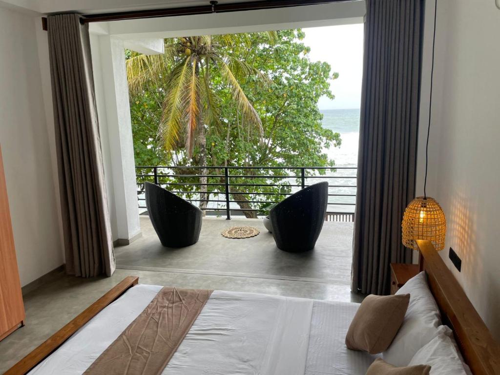 a bedroom with a bed and a view of the ocean at Bloom Beach Villa in Batigama