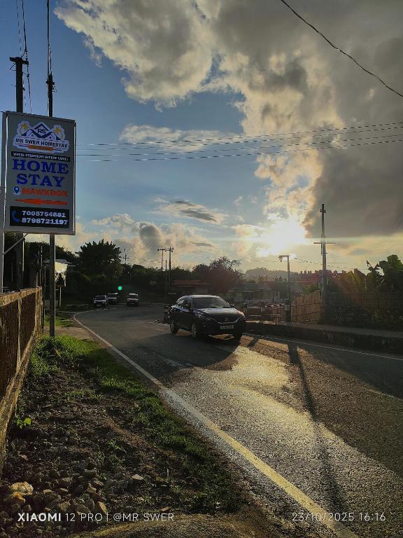 a car driving down a road with a sign at MR SWER Homestay in Shillong