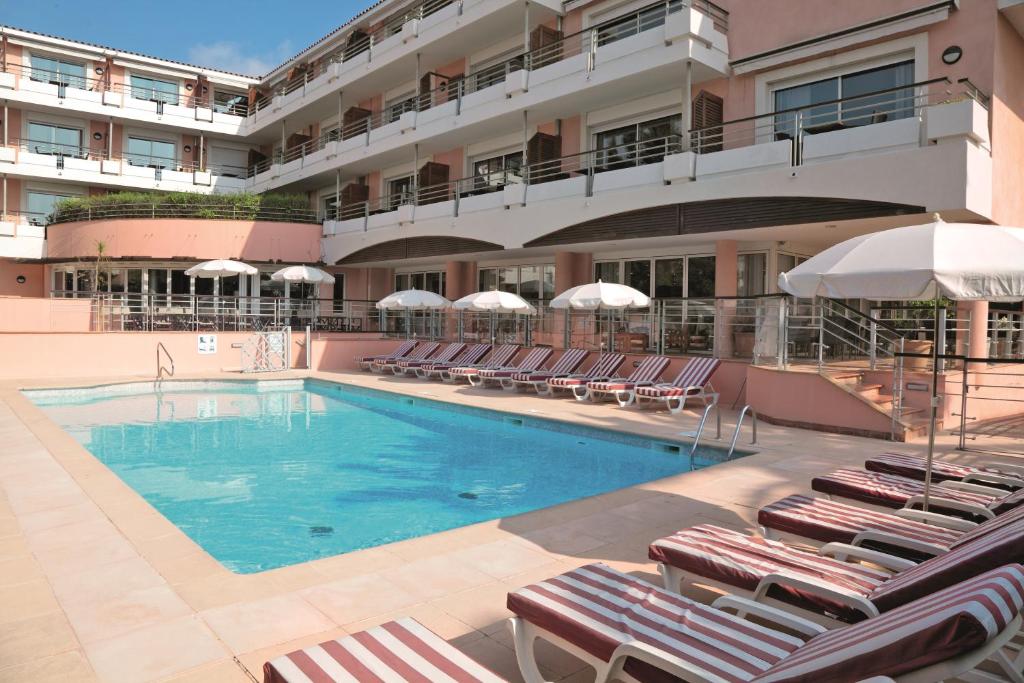 une piscine avec des chaises longues et un hôtel dans l'établissement Zenitude Hôtel-Résidences Le Cannet, au Cannet