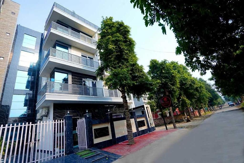 a tall white building with a tree in front of it at Expo Mart Inn in Greater Noida