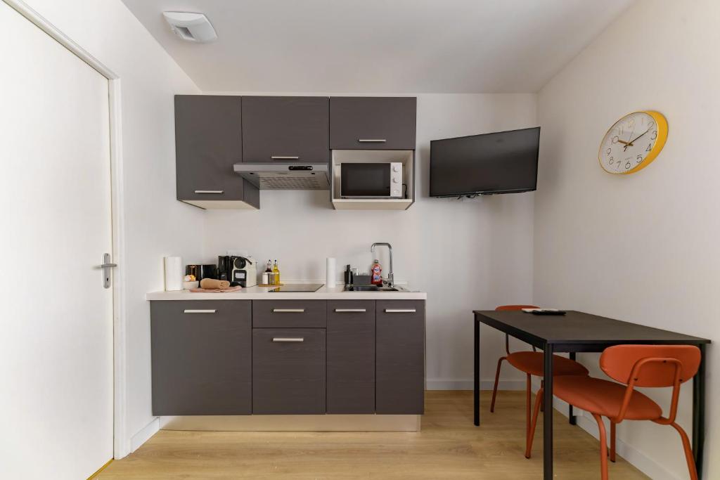 a kitchen with a table and a clock on the wall at Résidence Louis B - Appartements design et climatisés in Vichy