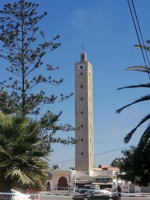 a tall tower with cars parked in front of it at Dar Sofiane in Sidi Bouzid