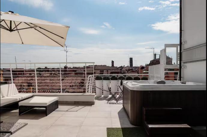 a balcony with a bath tub and an umbrella at L'attico dell'Edera in Bologna
