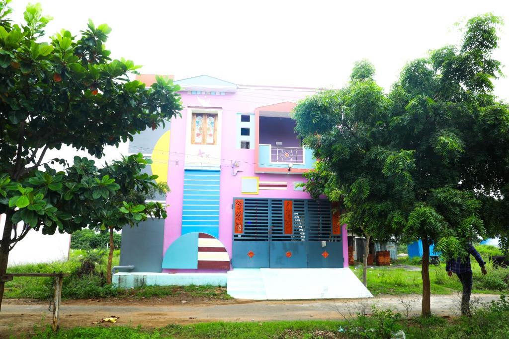 een kleurrijk huis met een boom ervoor bij Nandhi home stay in Tiruvannamalai