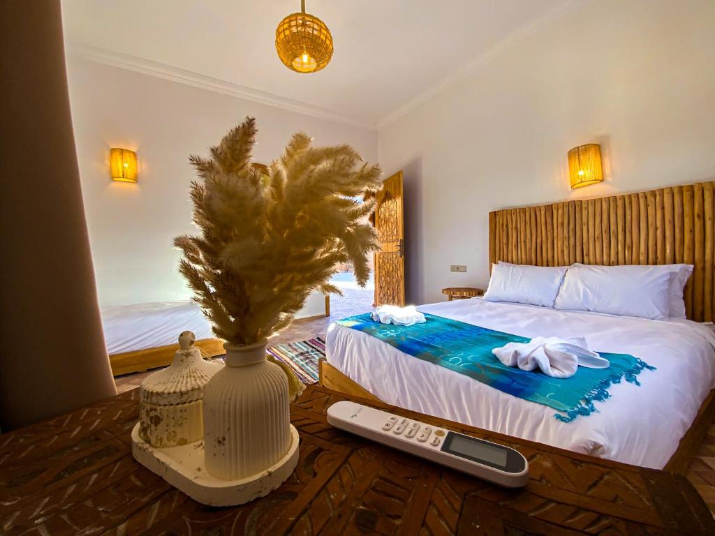 a bedroom with a bed with a vase and a remote control at Dar Bikouch in Ouarzazate