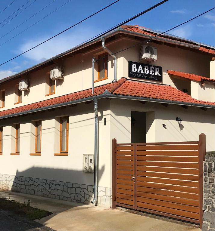 a building with a gate and a barber sign on it at Babér Vendégház Tokaj in Tokaj