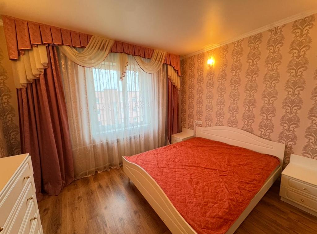 Un dormitorio con una cama con sábanas rojas y una ventana. en Rahu 2838 Apartment, en Narva