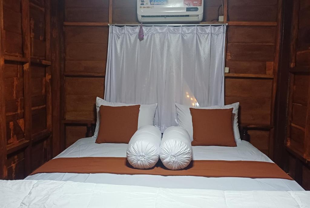 a bedroom with a bed with white pillows and a window at Villa Ilham Ketembong in Tetebatu