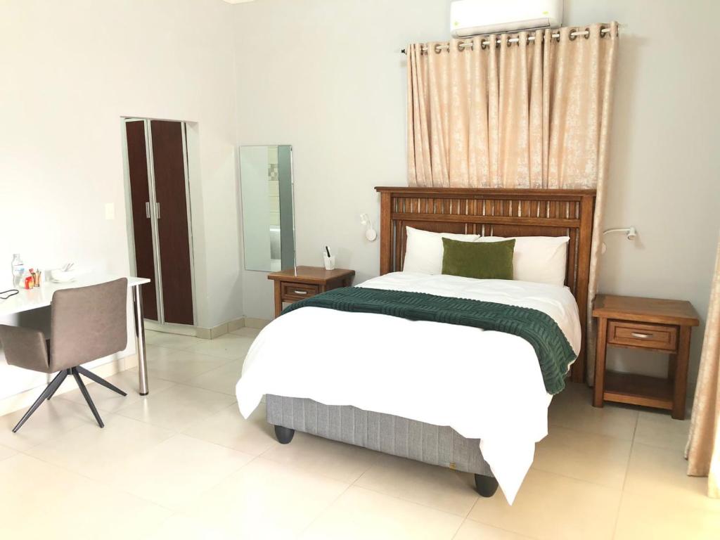 a bedroom with a bed and a table and a desk at Divine Boutique Hotel in Rustenburg