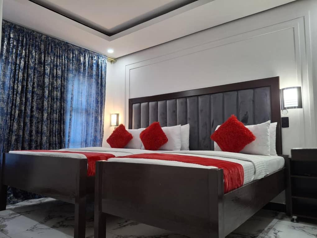 a bedroom with a large bed with red pillows at Silk Mbare Guest House in Manzini