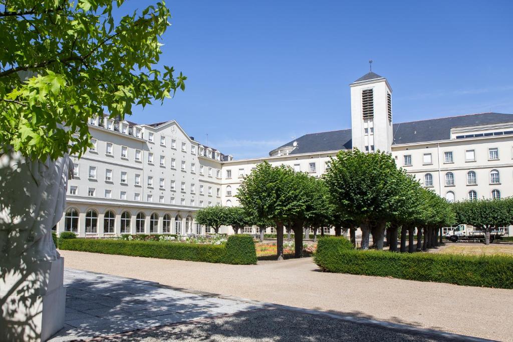 アンジェにあるHostellerie Bon Pasteurの目の前に木々が植えられた白い大きな建物