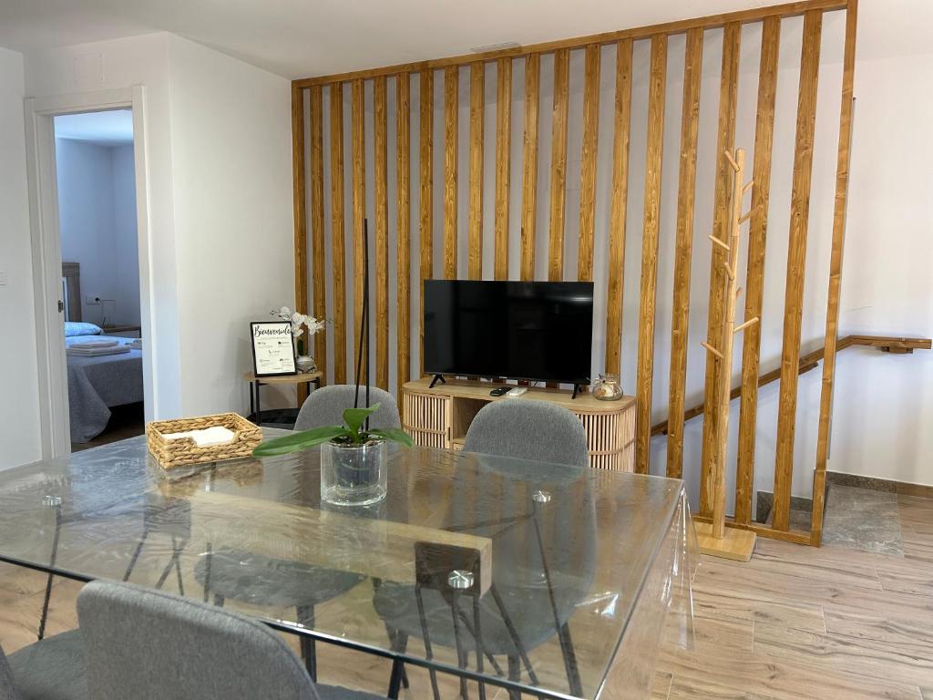 a dining room with a glass table and a television at Apartamentos el Sabinar II in Anchuela del Campo