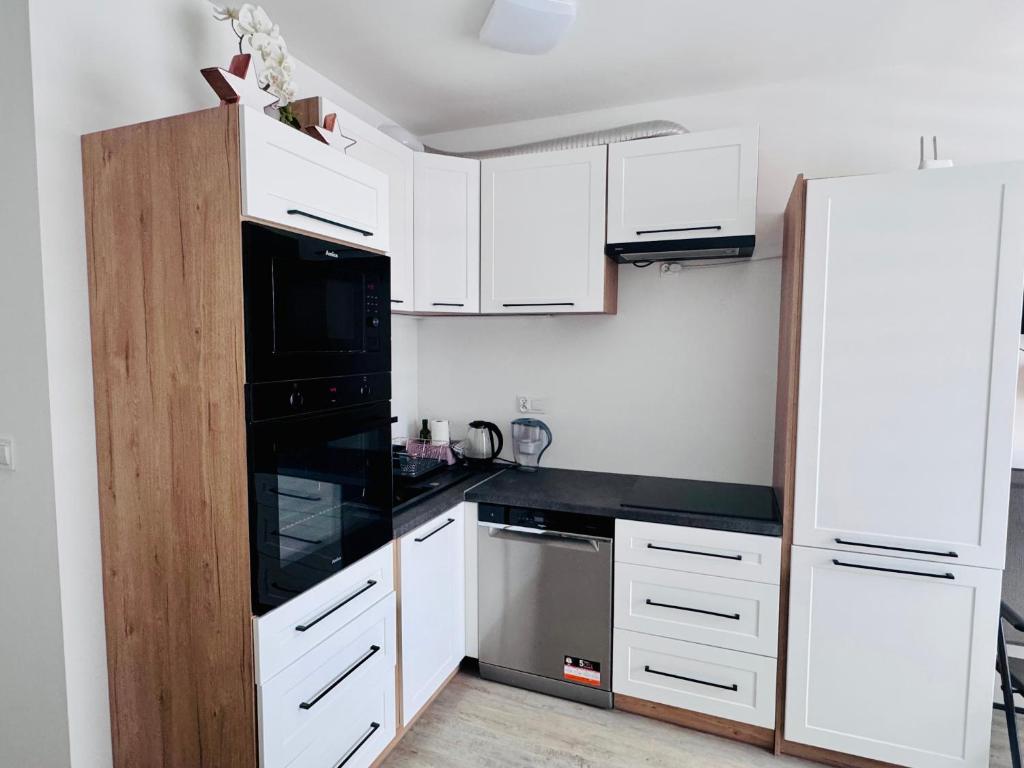 a kitchen with white cabinets and a black appliance at Perła Mórz 74 in Sianozety