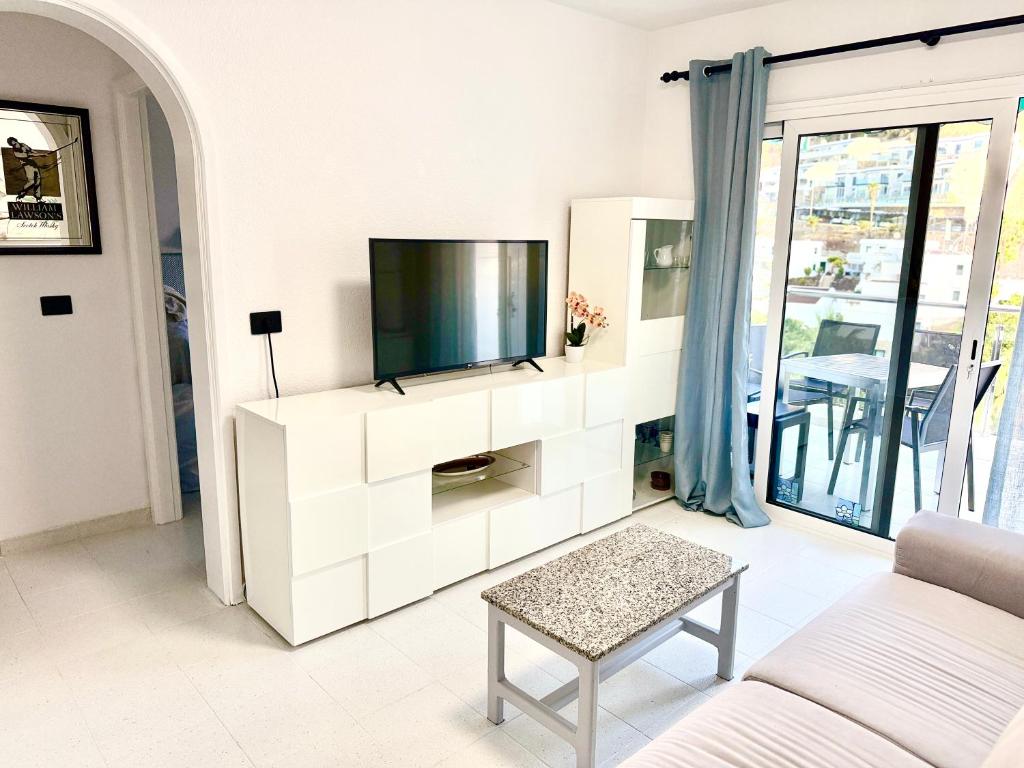 a living room with a tv on a white cabinet at Miami Beach in Mogán