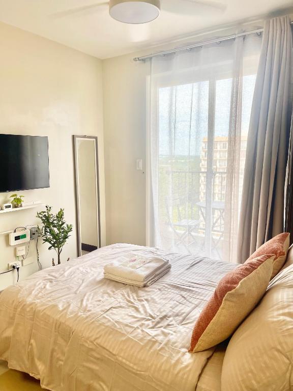 a bedroom with a large bed with a window at Minimalist Studio-Type Condo Unit at Saekyung Marigondon in Suba