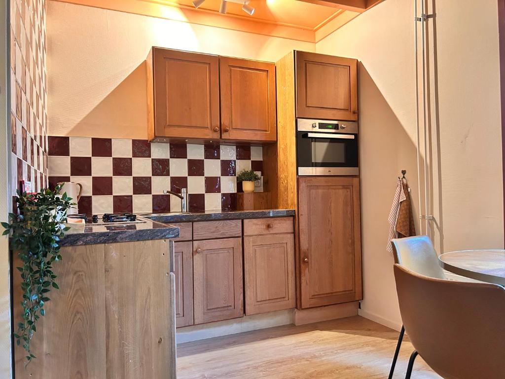 Una cocina con armarios de madera, fregadero y horno. en Sfeervol huisje in Friesland, en Haulerwijk