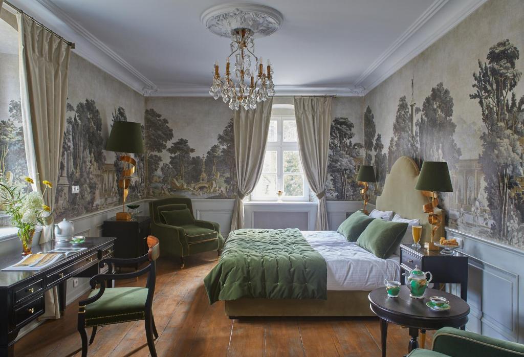 a bedroom with a bed and a desk and a chandelier at Zamek Sarny - Schloss Scharfeneck in Kłodzko