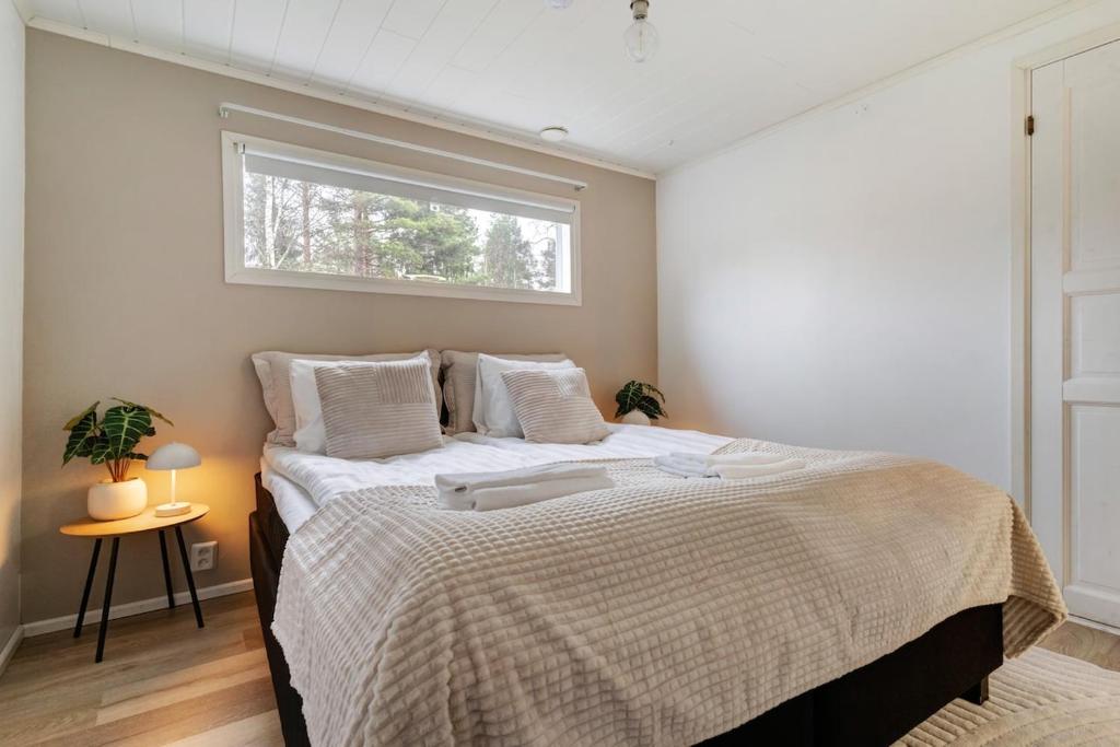 Un dormitorio con una cama grande con ventana. en Cozy Lapland Hideaway, 2BDR, Wifi & Parking, en Rovaniemi
