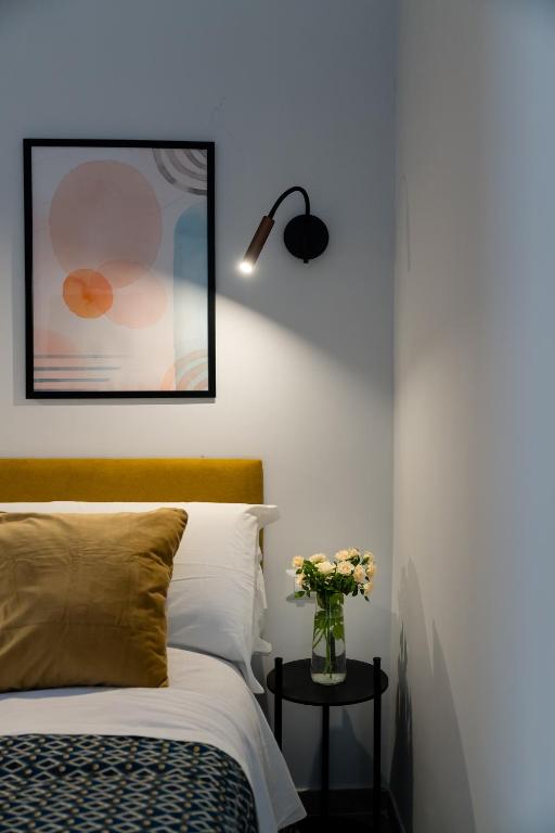 那不勒斯Plebiscito Luxury Rooms的一间卧室,配有一张床,桌子上放着花瓶