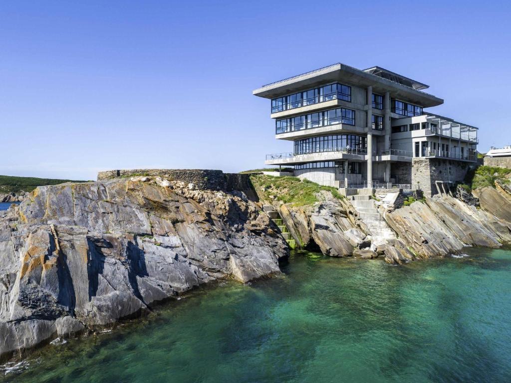 ル・コンケにあるSainte-Barbe Hotel & Spa Le Conquet - MGallery Collectionの水の横の断崖の上の建物