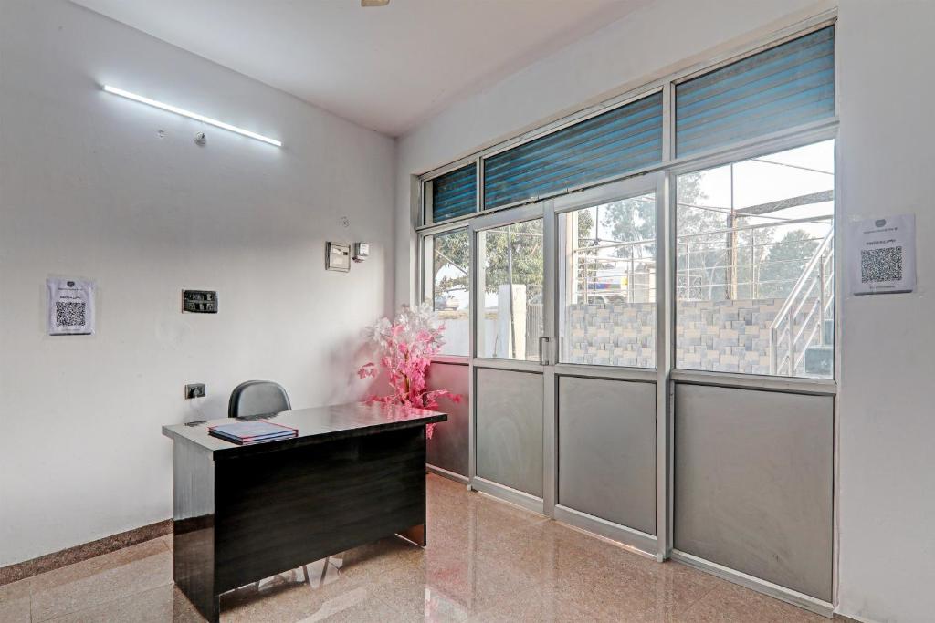 an office with a desk and a large window at Hotel O Mahadevi Lawn in Lucknow