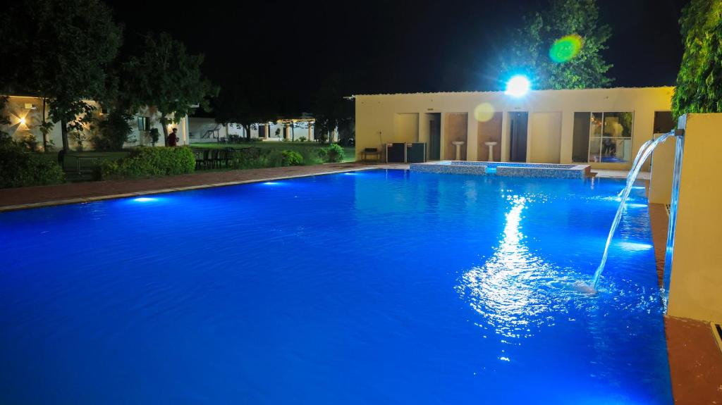 een groot blauw zwembad 's nachts met een fontein bij The Lala Hotel and Resort in Pushkar
