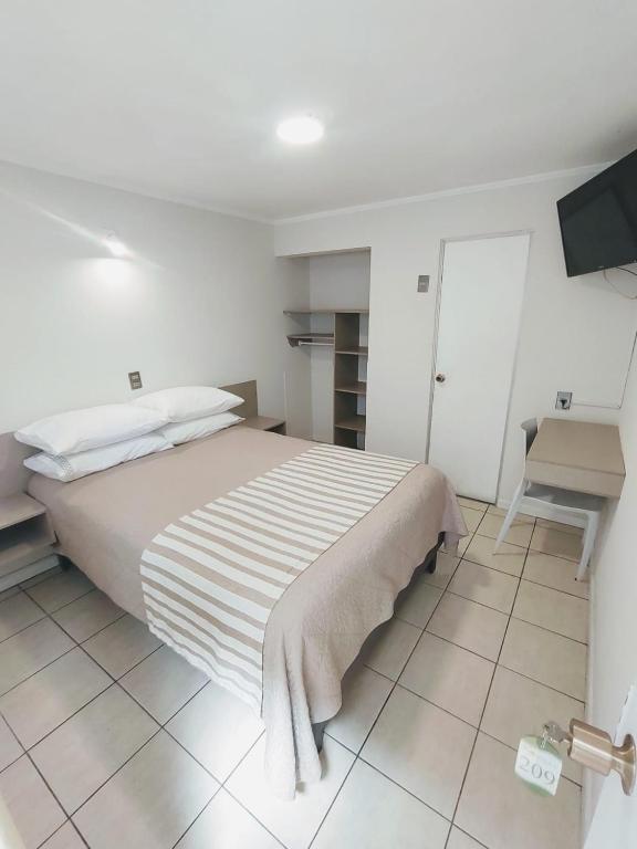 a bedroom with a bed and a desk and a television at Hotel Frontera in Antofagasta