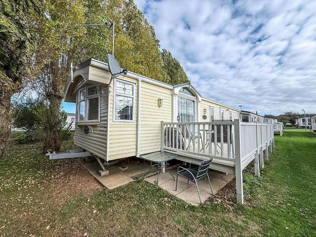 une maison jaune avec un porche et une chaise dans l'établissement Lovely Caravan At Manor Park, Nearby Hunstanton Beach In Norfolk Ref 23029T, à Hunstanton