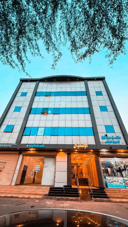 a large building with blue windows on a street at شقق زهرة النزلاء المخدومة in Buraydah