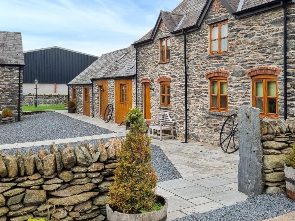 an old stone house with a stone wall at The Dairy -Uk50616 in Cynwyd