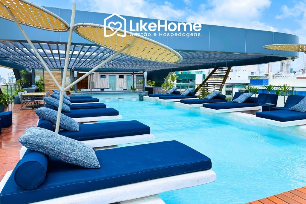 a swimming pool with blue chairs and umbrellas on a building at Setai Aquamaris - LikeHome Hospedagens in Tambaú