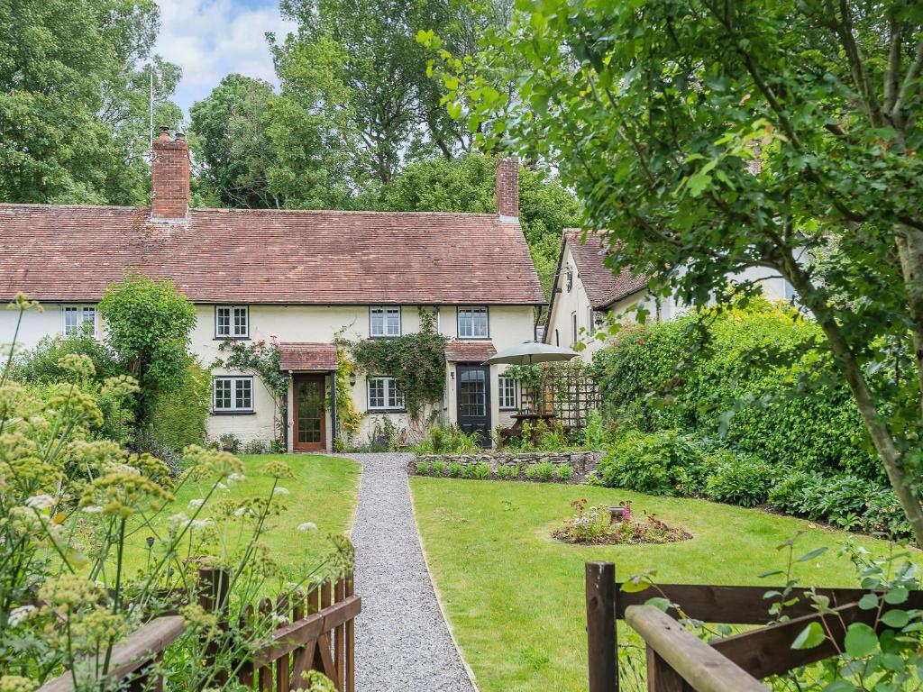 a white house with a garden and a fence at Bourne Farm Cottage in Blandford Forum