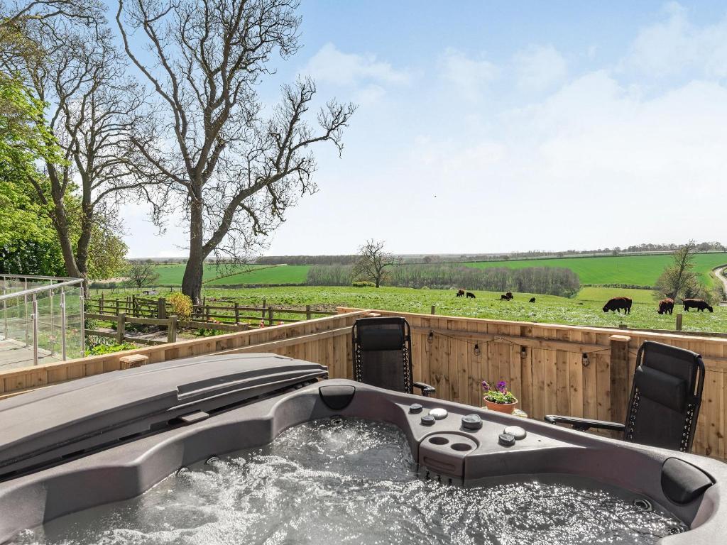 a hot tub in the middle of a field with cows at Lizzie's Cottage in Skendleby