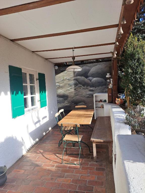 a wooden table and chairs on a patio with a mural at Bierfrauhäusl in Antdorf