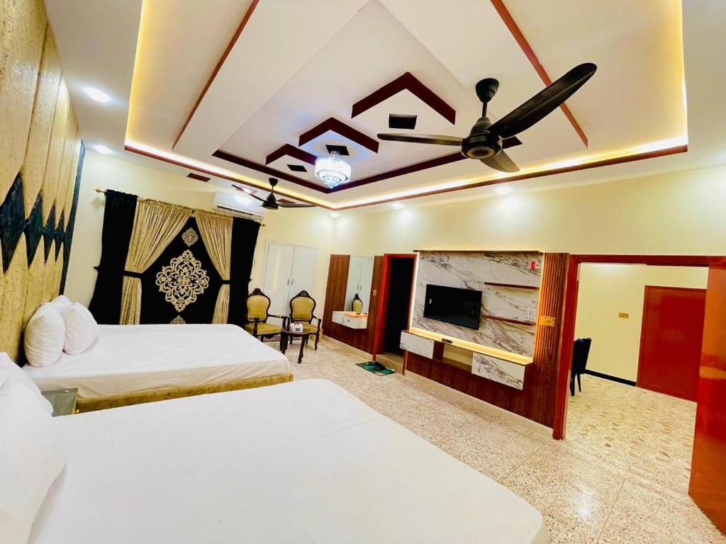 a bedroom with two beds and a ceiling fan at Sunshine Guest House in Dargai