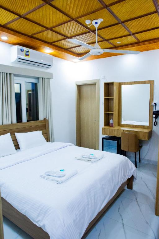 a bedroom with a large white bed and a tv at Darunique Inn in Nizwa