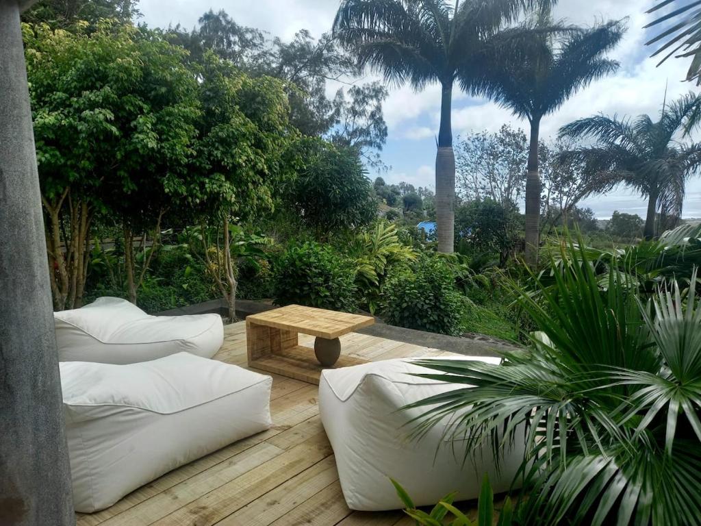a patio with couches and a table and palm trees at Les Hauteurs de Brûlée in Rodrigues Island