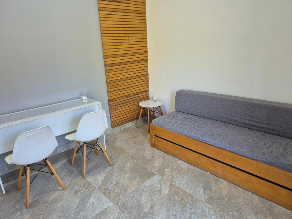 a bedroom with a bed and two chairs at Suíte Cambury in São Sebastião
