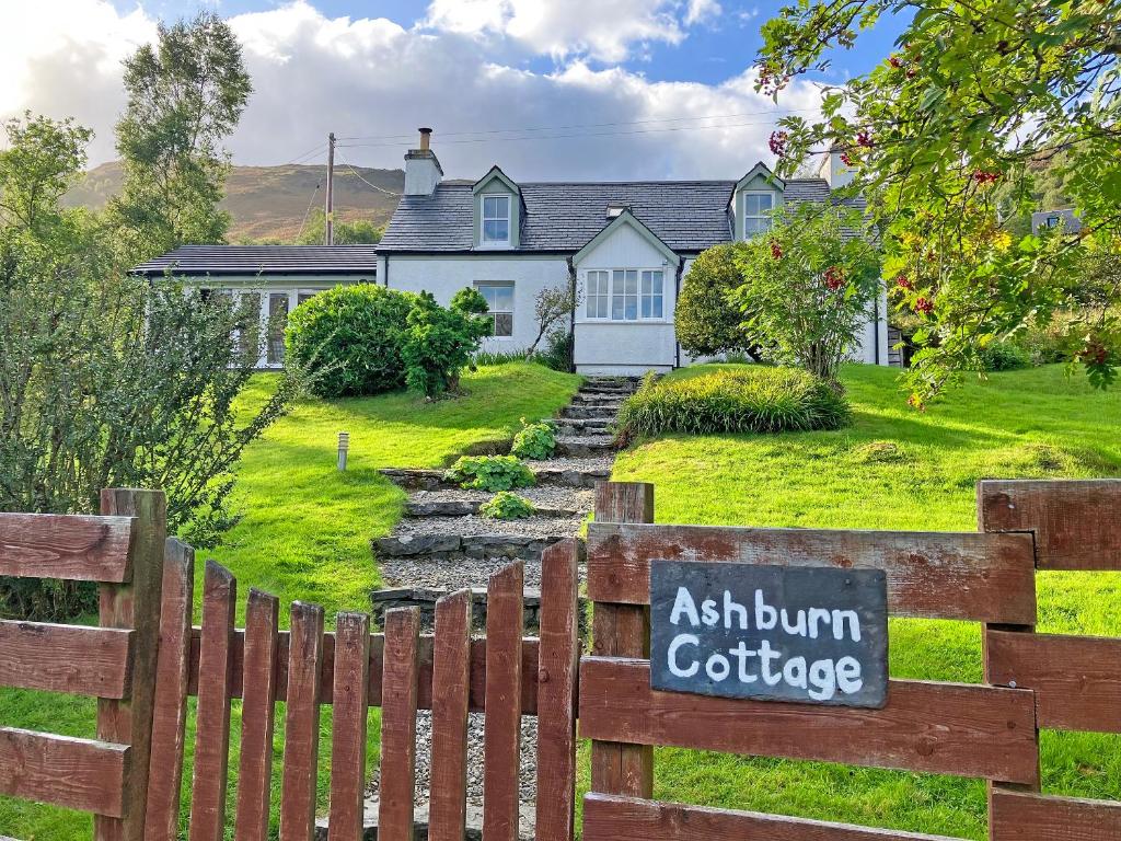 un panneau sur une clôture devant une maison dans l'établissement Ashburn Cottage, à Sallachy