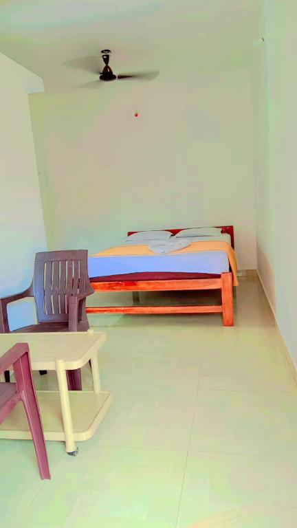 a bedroom with a bed and a table and a chair at Krishna Guest House in Arambol