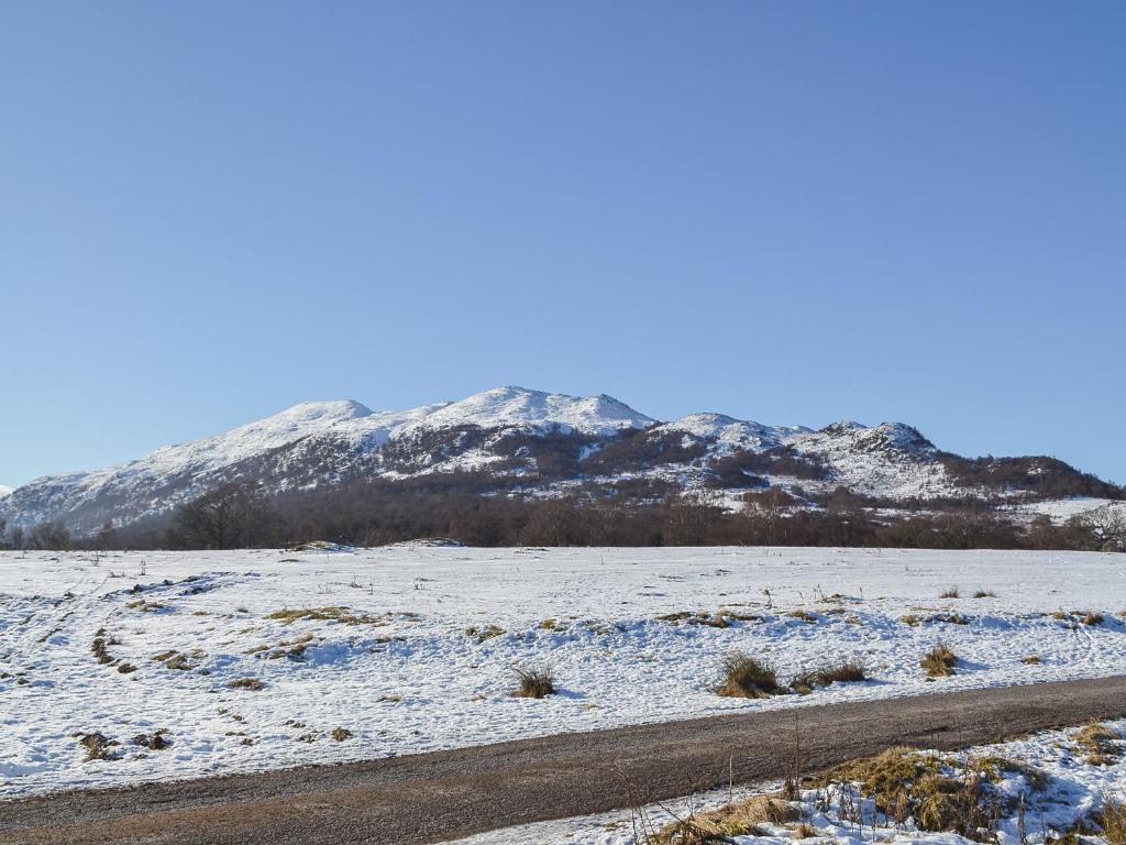 a snowy field with a mountain in the background at Bruich Cottage in Newtonmore