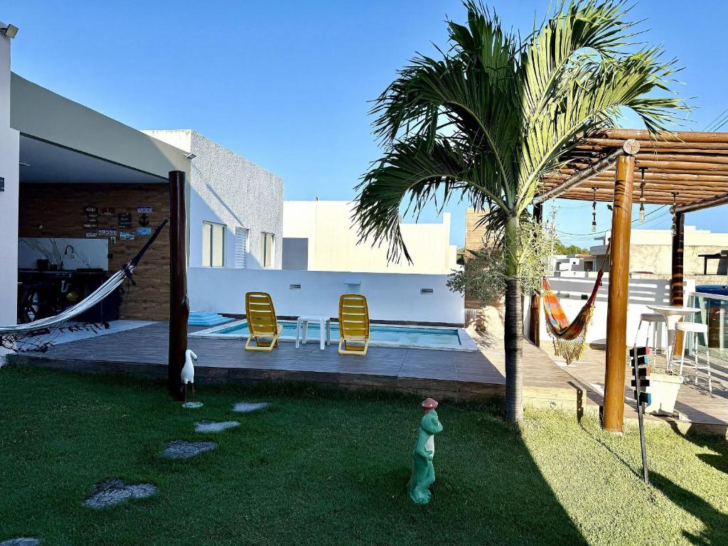ein Haus mit einem Garten mit Hängematte und Palme in der Unterkunft Brisas Beach casa 05 in Praia do Frances