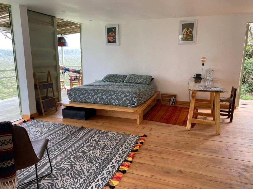 a bedroom with a bed and a table and a rug at Embibi Campground, Cabin and Retreat in Ngong