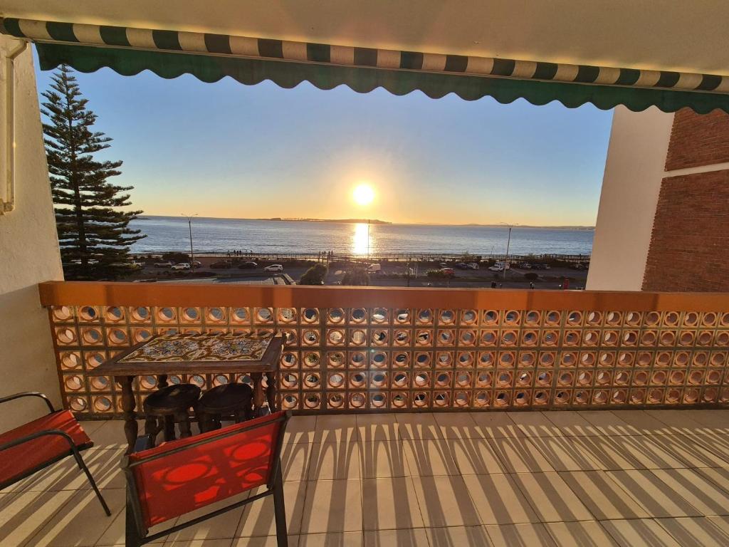 een balkon met een tafel en stoelen en uitzicht op de zonsondergang bij Apart Edificio Vanguardia frente al mar in Punta del Este