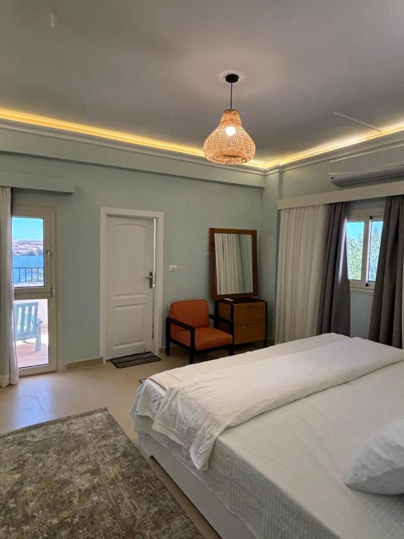 a bedroom with a bed and a chair and windows at Golden Sun House II in Abu Simbel