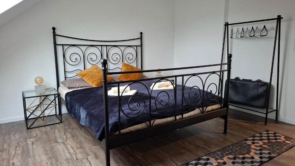 a bedroom with a black bed with blue sheets and orange pillows at 2 Zimmer Apartment - zentral und ruhig - nahe VW, Autostadt, Parkplatz & WLAN, CityStay Wolfsburg - GTI in Wolfsburg