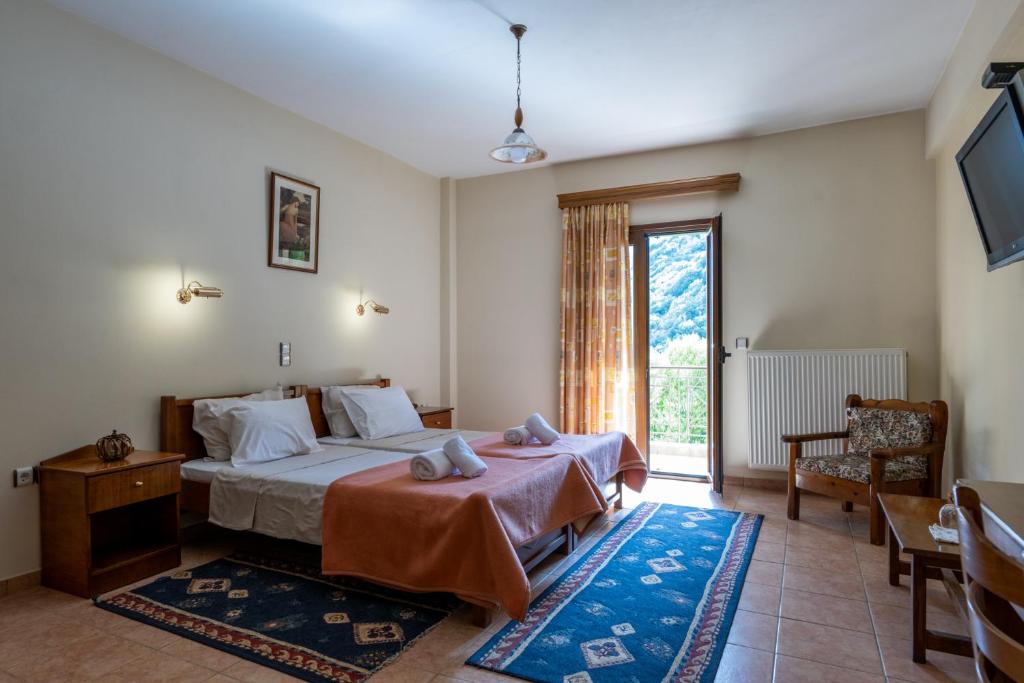 a bedroom with a bed and a chair and a window at Mountain Hotels "Achais" in Planitéron